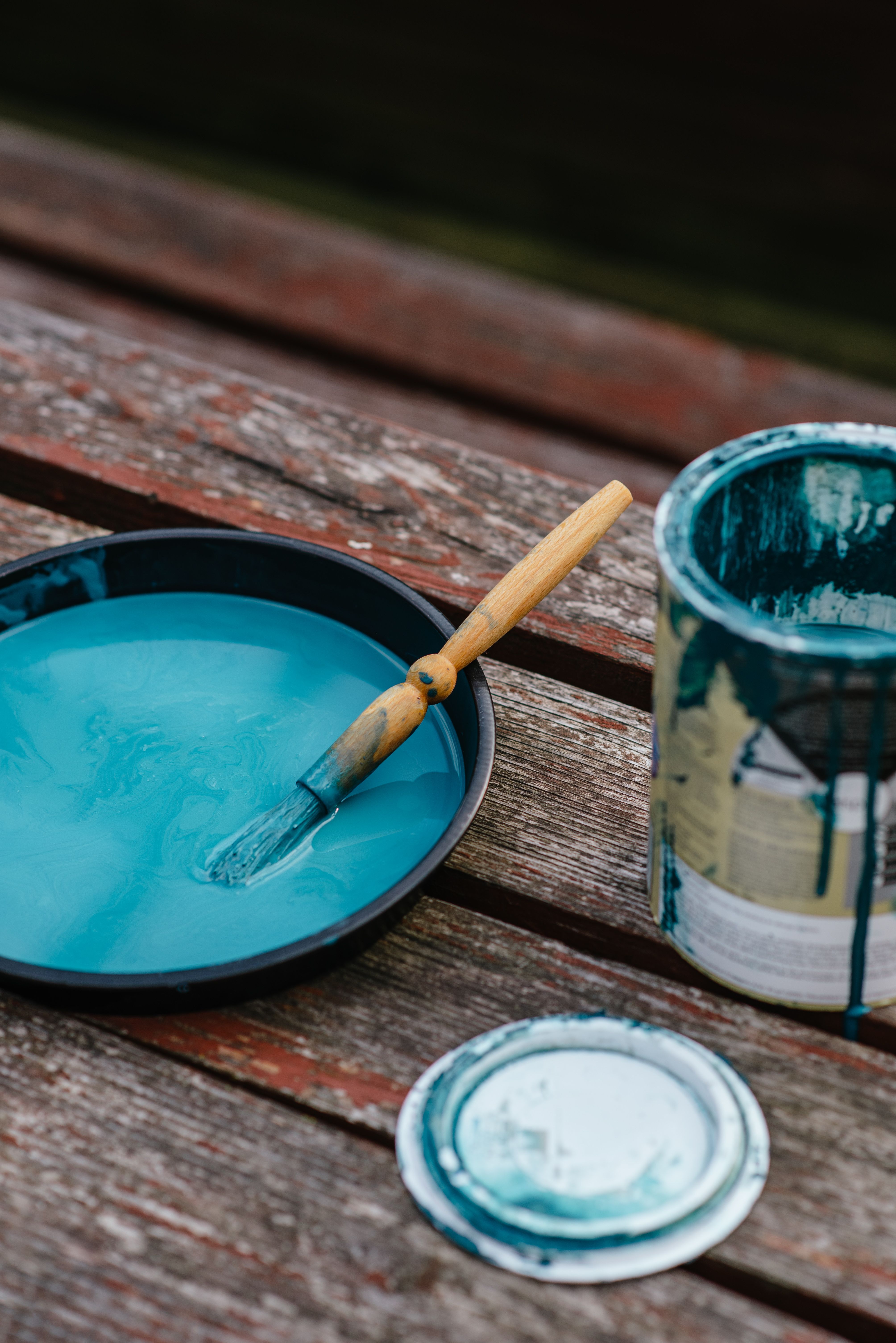 Paint brush in a tray of blue paint outdoors